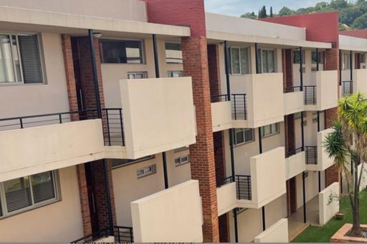 Exterior view of a multi-story apartment building featuring private balconies, brick accents, and metal railings.