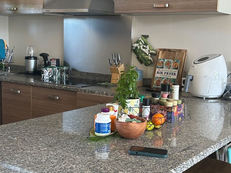 Modern kitchen featuring granite countertops, wood-finish cabinetry, and a stainless steel extractor fan with a built-in hob.