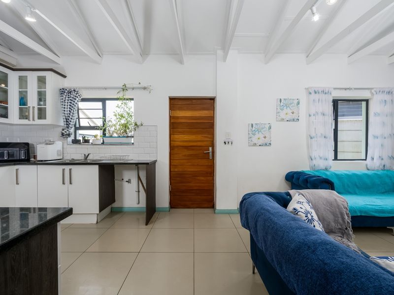 Open-plan living area featuring a modern kitchen with subway tile backsplash, granite countertops, and exposed beam ceilings, creating a bright and functional space.