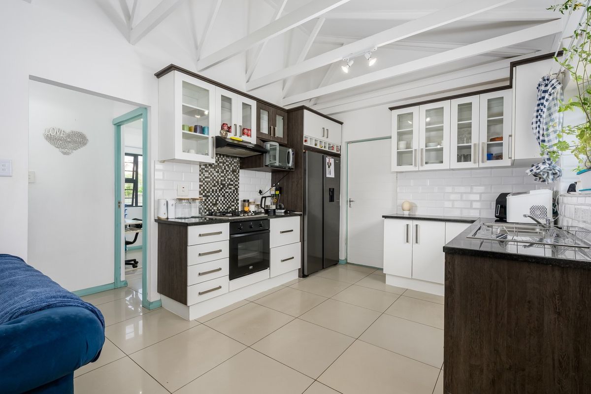 Modern kitchen featuring two-tone cabinetry, granite countertops, subway tile backsplash, built-in oven and hob, and high ceilings with exposed white trusses.
