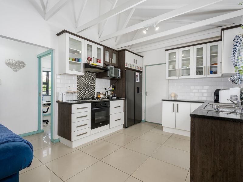Modern kitchen featuring two-tone cabinetry, granite countertops, subway tile backsplash, built-in oven and hob, and high ceilings with exposed white trusses.