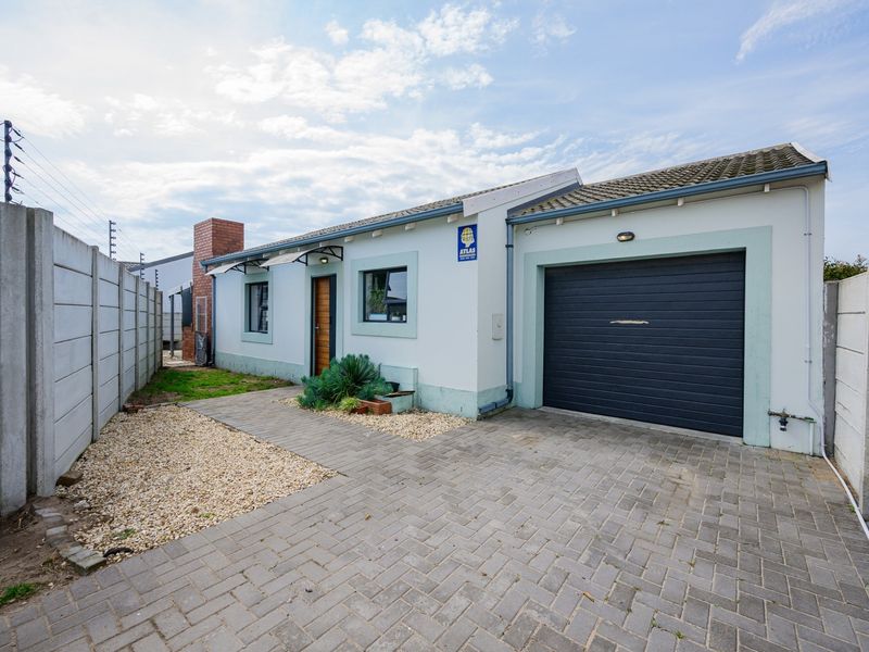 Front exterior view of the property featuring a paved driveway, single garage, and secure boundary wall with electric fencing.