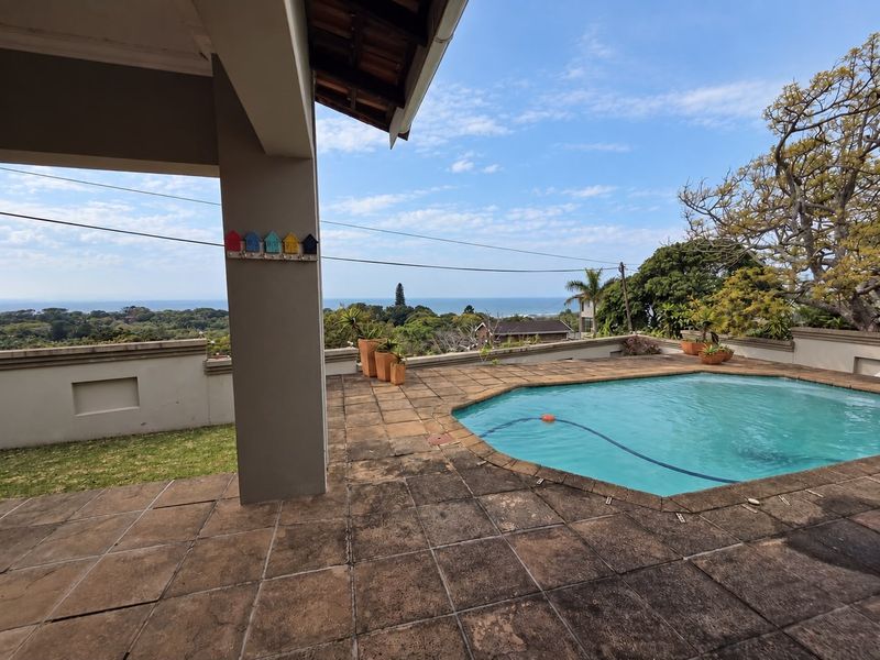 Outdoor pool area featuring a tiled patio, covered veranda space, and expansive coastal views.
