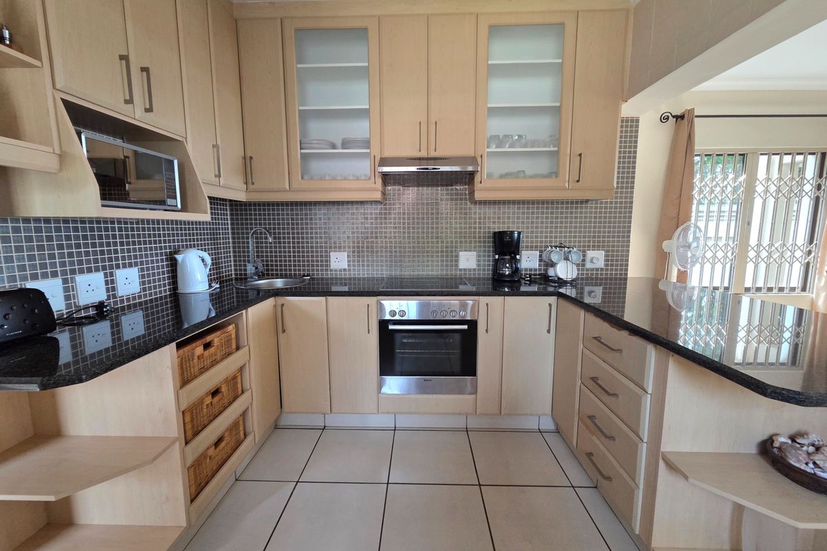 A well-maintained kitchen featuring light wood cabinetry, granite countertops, a mosaic tile backsplash, and integrated stainless steel appliances.