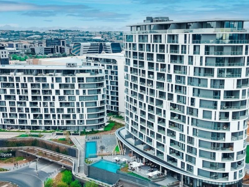 Aerial view of a modern apartment complex featuring multiple high-rise buildings, swimming pool facilities, and landscaped outdoor areas.