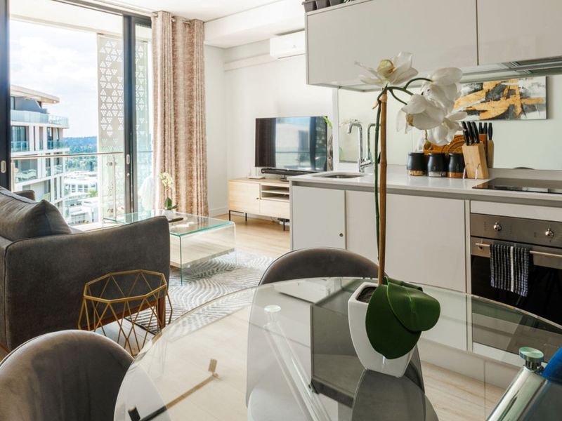 Modern open-plan apartment featuring a sleek kitchen with built-in appliances, flowing into a bright living area with access to a private balcony.