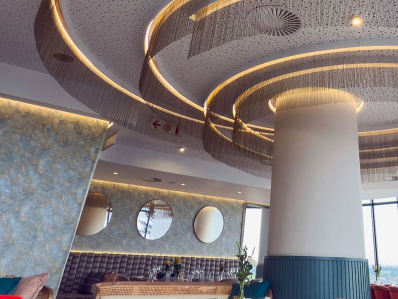 Sophisticated clubhouse interior featuring a striking circular ceiling design with integrated lighting, decorative chain accents, and elegant wall finishes.