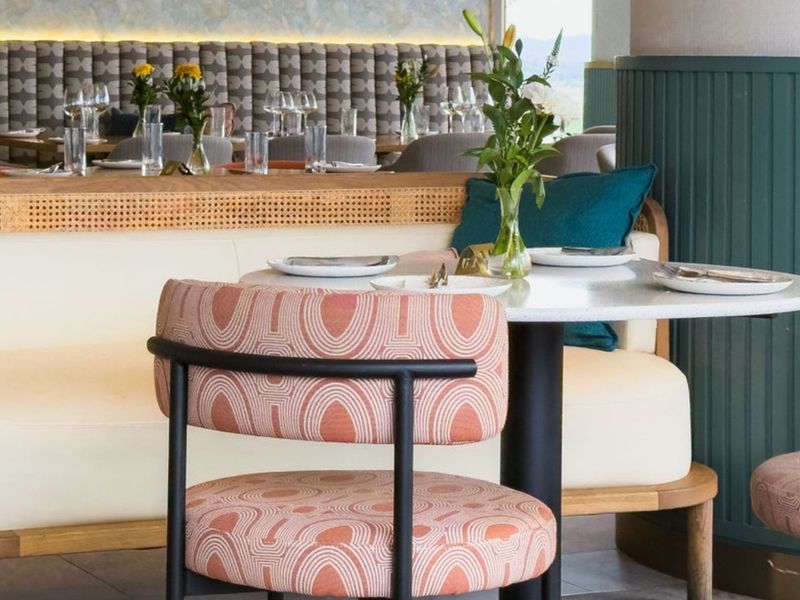 A stylishly designed interior space featuring custom upholstered banquette seating, decorative wainscoting, and modern recessed lighting, creating a sophisticated and inviting atmosphere.