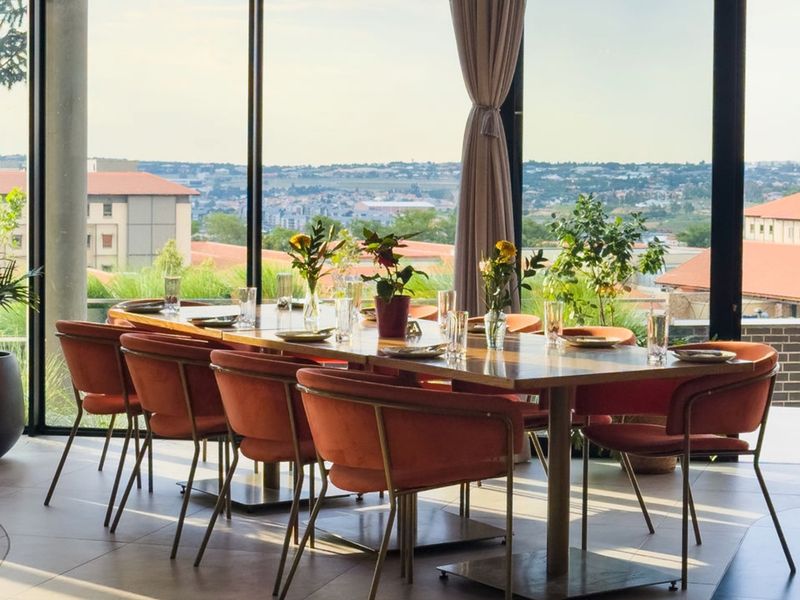A bright dining area featuring floor-to-ceiling windows that offer expansive views of the surrounding landscape and neighborhood.