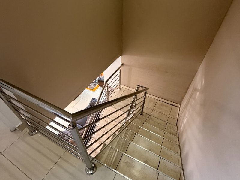 A staircase featuring tiled steps and a modern stainless steel balustrade, providing a clean transition between levels in the home.