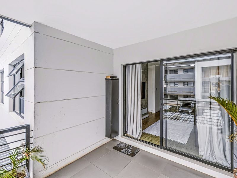 A covered balcony featuring tiled flooring, a metal balustrade, and sliding glass doors providing access to the interior living space.