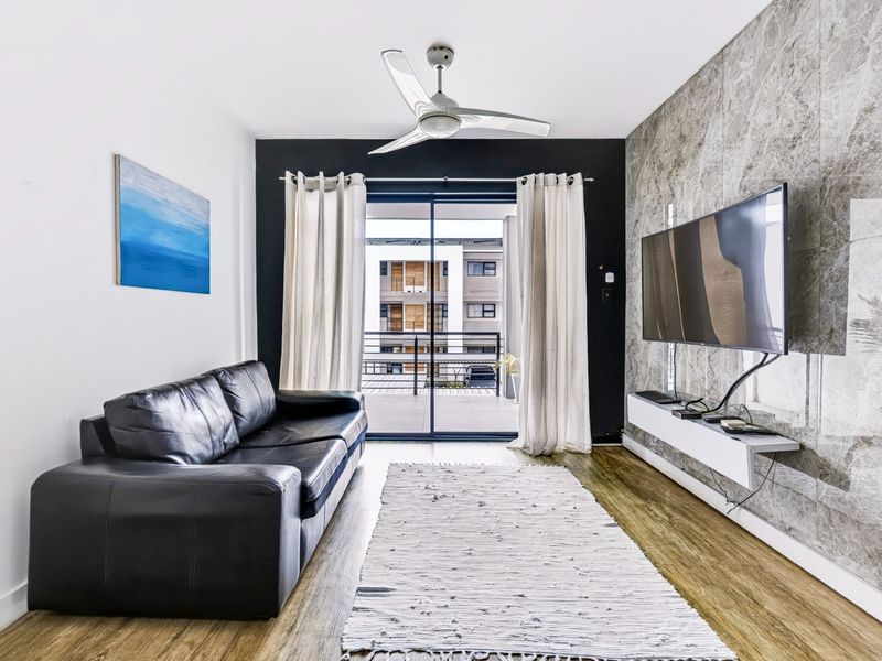 Modern living room featuring a marble-effect feature wall, floating media console, ceiling fan, and sliding glass doors leading to a balcony.