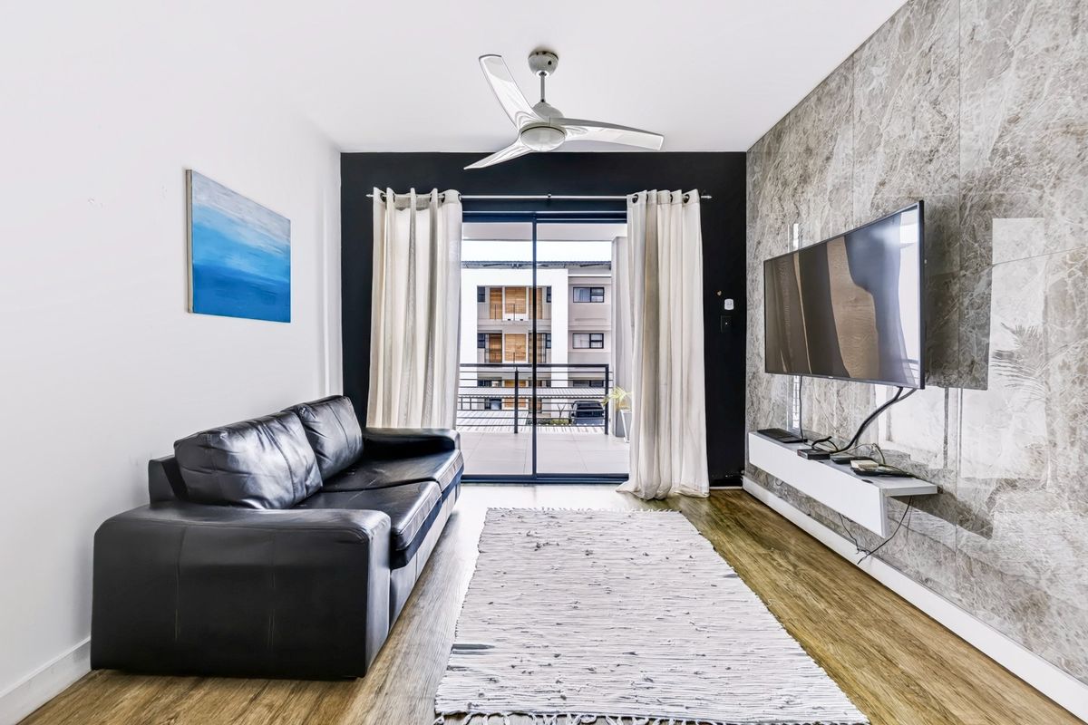 Modern living room featuring a marble-effect feature wall, floating media console, ceiling fan, and sliding glass doors leading to a balcony.