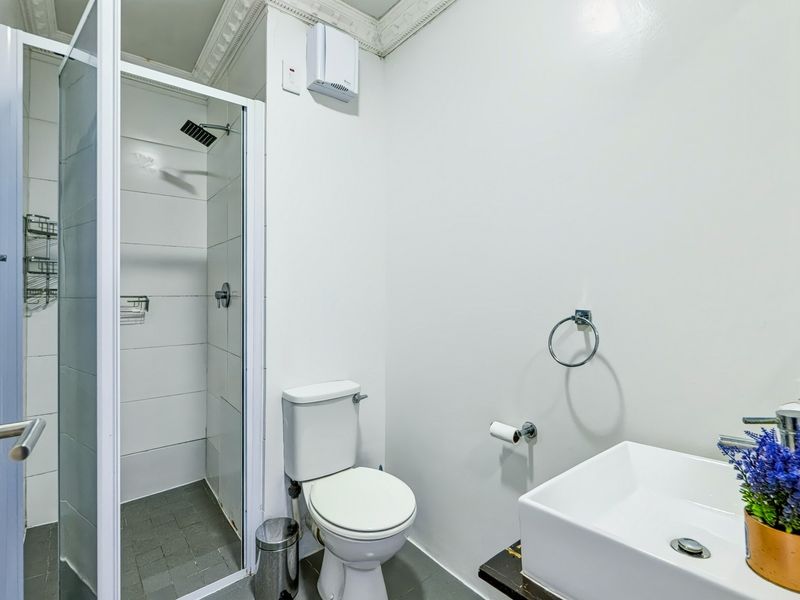 A clean and functional bathroom featuring a glass-enclosed shower, a modern wash basin, and a standard toilet with tiled finishes.