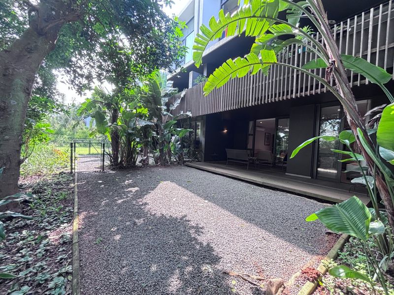 Rear exterior view of the apartment featuring a private gravel garden, timber decking, and modern vertical slat screening for privacy.