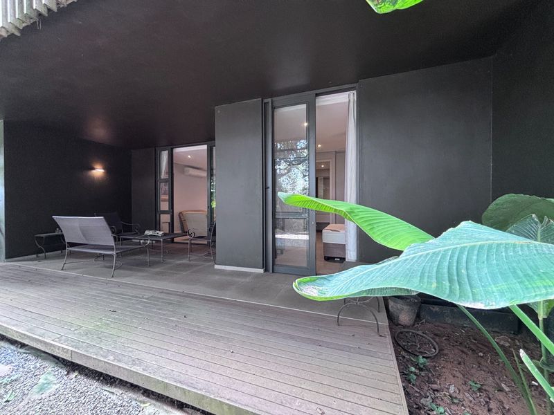 A covered patio area featuring timber decking and sliding glass doors providing direct access to the interior living space.