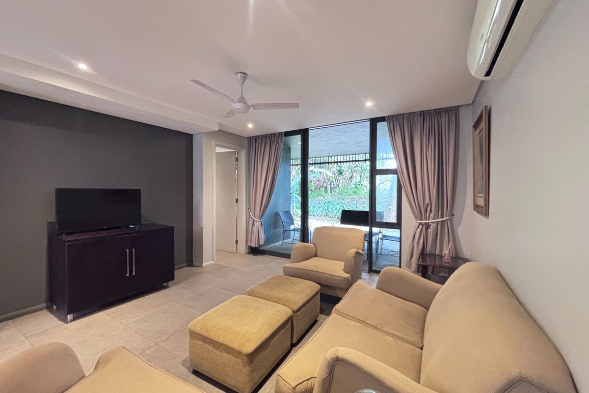 A comfortable living room featuring tiled flooring, a ceiling fan, split-system air conditioning, and large sliding glass doors providing access to the patio.