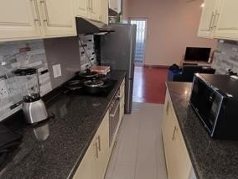 Open-plan kitchen featuring granite countertops, built-in cabinetry, and a mosaic tile backsplash, flowing into the adjacent living area.