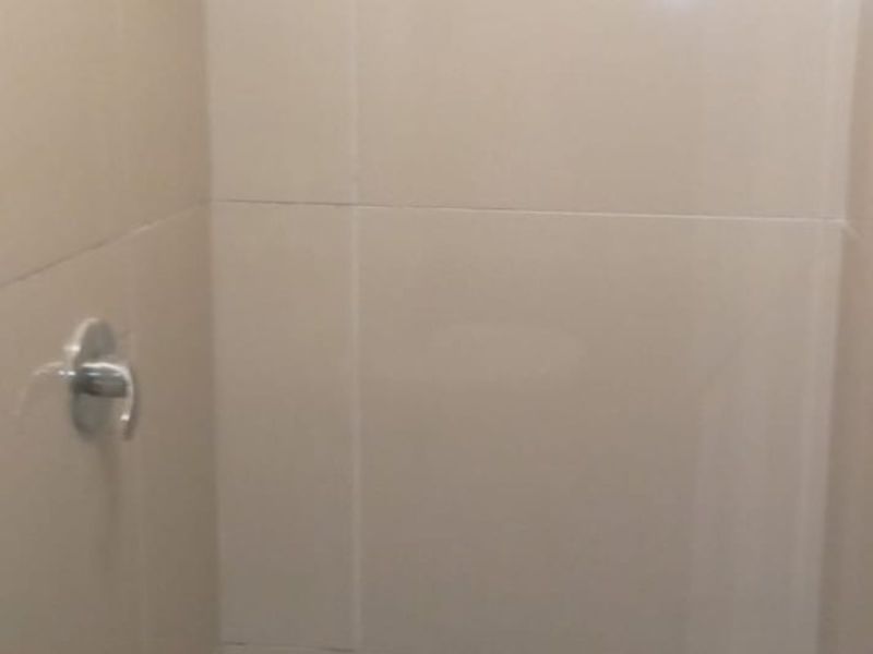 A compact shower enclosure featuring neutral wall tiles, a mosaic tiled floor, and standard chrome shower fixtures.