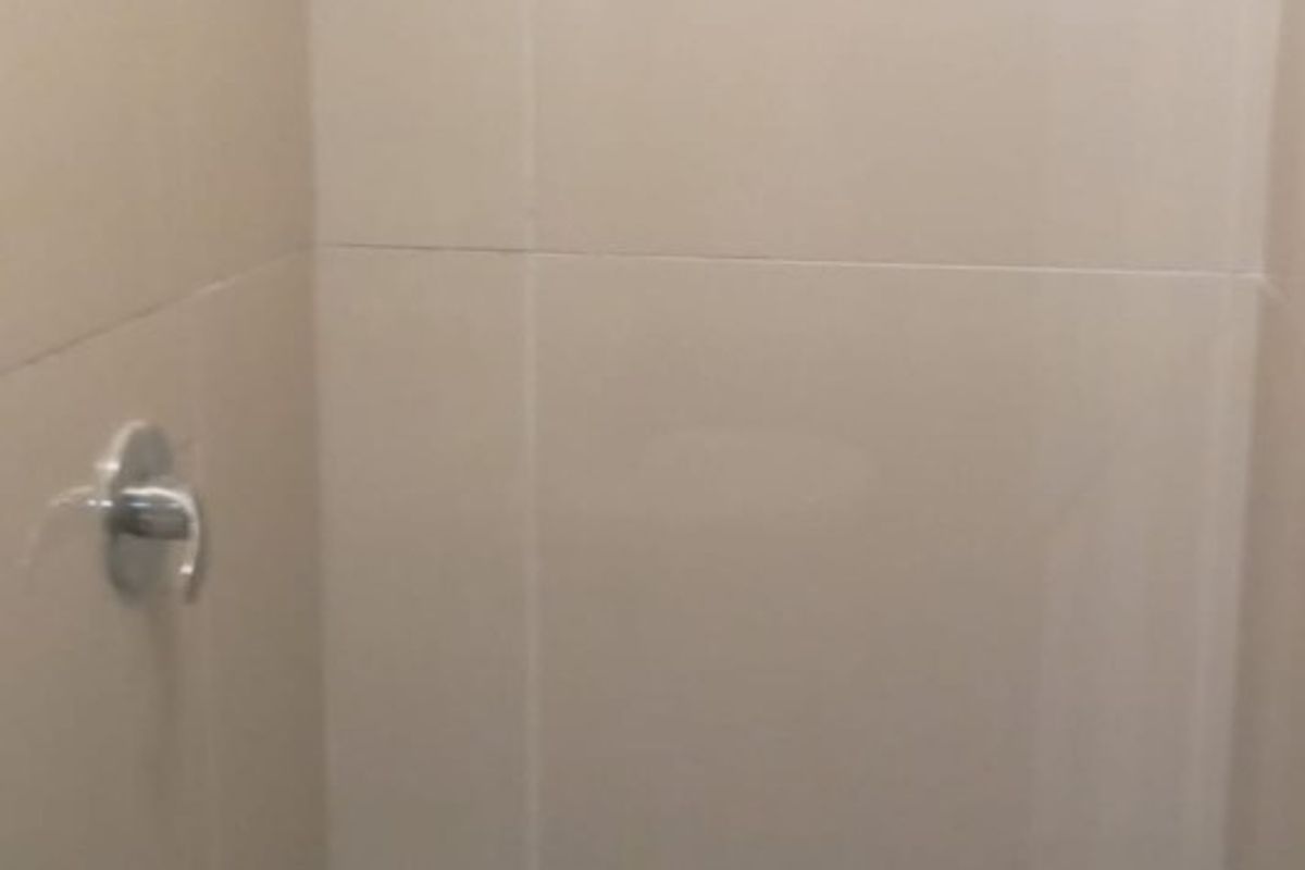 A compact shower enclosure featuring neutral wall tiles, a mosaic tiled floor, and standard chrome shower fixtures.