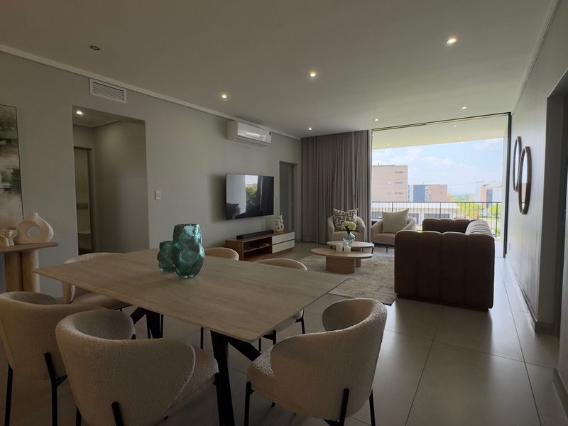 Spacious open-plan living and dining area featuring modern tiled floors, recessed lighting, and seamless access to a private balcony.