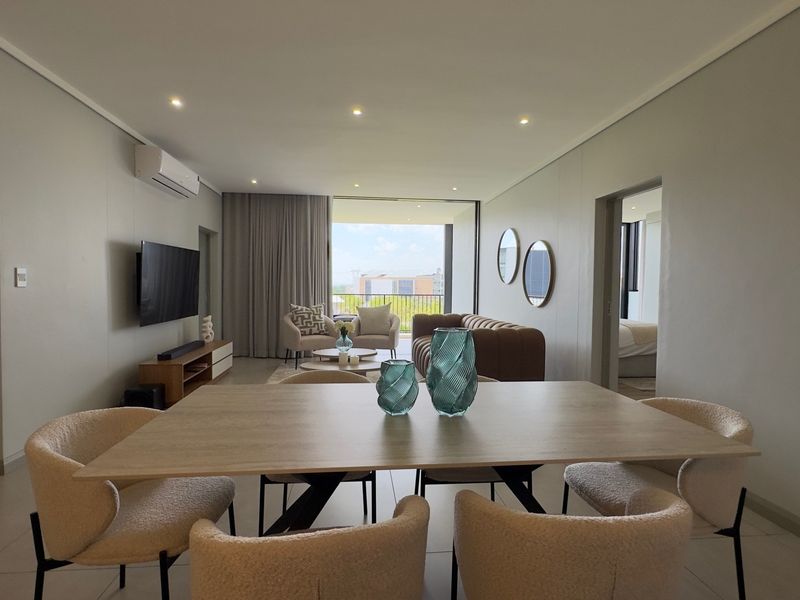 Spacious open-plan living and dining area featuring modern tiled floors, recessed lighting, and seamless access to a private balcony.