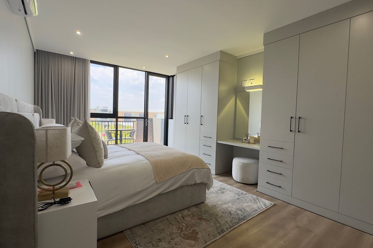 Modern bedroom featuring extensive built-in cabinetry with integrated vanity, recessed lighting, air conditioning, and direct access to a private balcony.