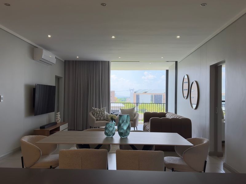 Spacious open-plan living and dining area featuring modern recessed lighting, air conditioning, and large sliding doors leading to a balcony with scenic views.