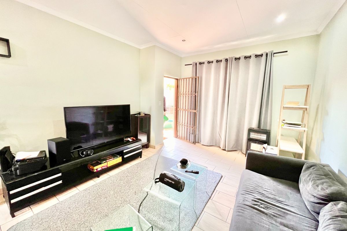 A bright living room featuring tiled flooring, recessed lighting, and direct access to an outdoor area through a secure gate.