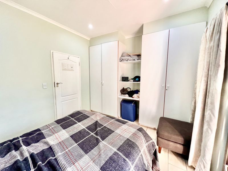 A functional bedroom featuring built-in white cabinetry, tiled flooring, and recessed ceiling lighting, offering a clean and practical living space.