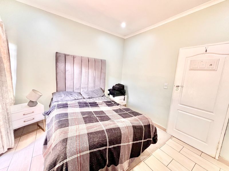 A well-maintained bedroom featuring neutral wall tones, tiled flooring, and recessed ceiling lighting, providing a clean and functional living space.