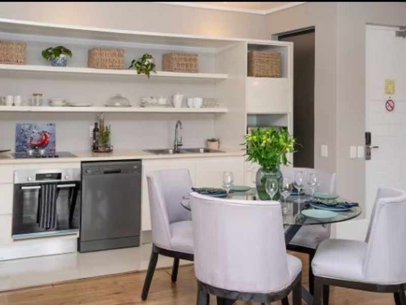 Modern open-plan kitchen and dining area featuring sleek cabinetry, open shelving, integrated appliances, and durable laminate flooring.