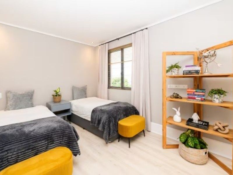 A well-maintained bedroom featuring light-toned laminate flooring, recessed ceiling lighting, and neutral wall finishes, providing a bright and comfortable living space.