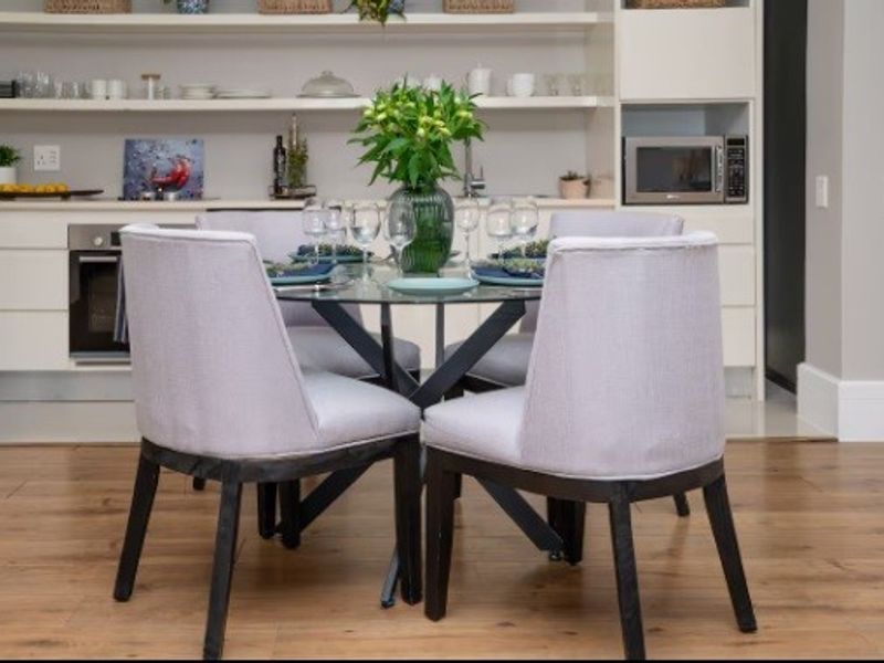 Modern open-plan kitchen and dining area featuring sleek cabinetry, built-in appliances, open shelving, and warm laminate flooring.