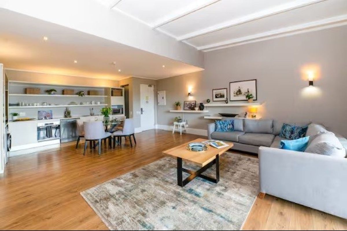 Spacious open-plan living area featuring hardwood flooring, integrated kitchen appliances, built-in shelving, and modern recessed lighting throughout the combined kitchen and lounge space.
