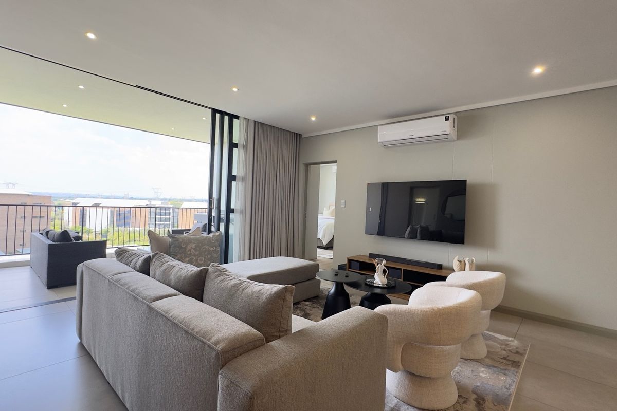 Modern living room featuring tiled floors, recessed lighting, a wall-mounted air conditioner, and large sliding doors opening onto a balcony with urban views.