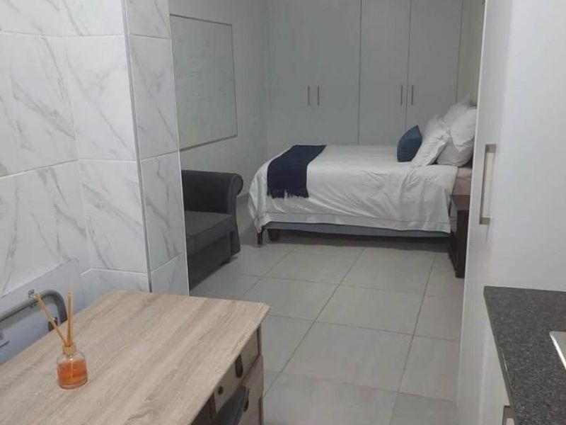 An open-plan studio space featuring tiled flooring, built-in cupboards, and a compact kitchen area with modern wall finishes.