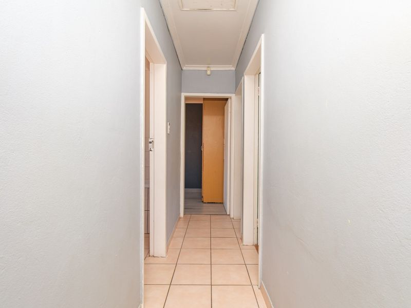 A functional hallway featuring tiled flooring and access to multiple rooms, presenting a neutral canvas for potential interior updates.