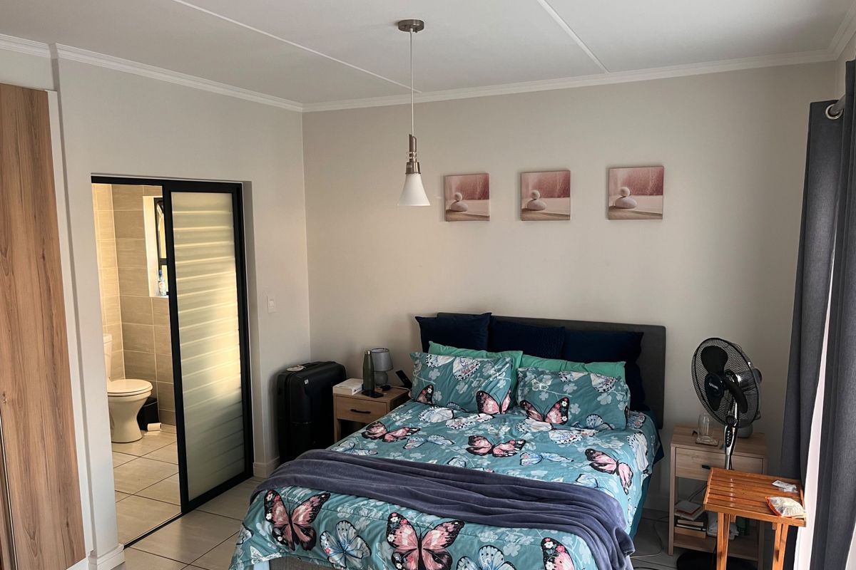 A well-maintained bedroom featuring tiled flooring, a built-in wardrobe, and an en-suite bathroom accessible via a sliding door.