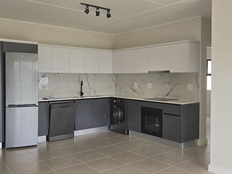 Modern kitchen featuring sleek two-tone cabinetry, marble-look splashback, integrated appliances, and neutral tiled flooring in an open-plan layout.