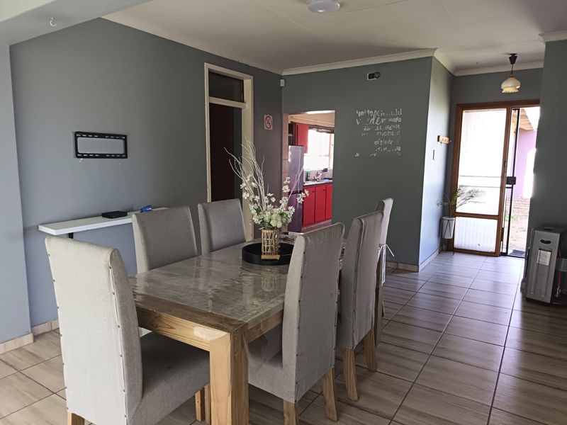 Dining area featuring tiled flooring, a built-in wall shelf, and direct access to the kitchen and outdoor area.