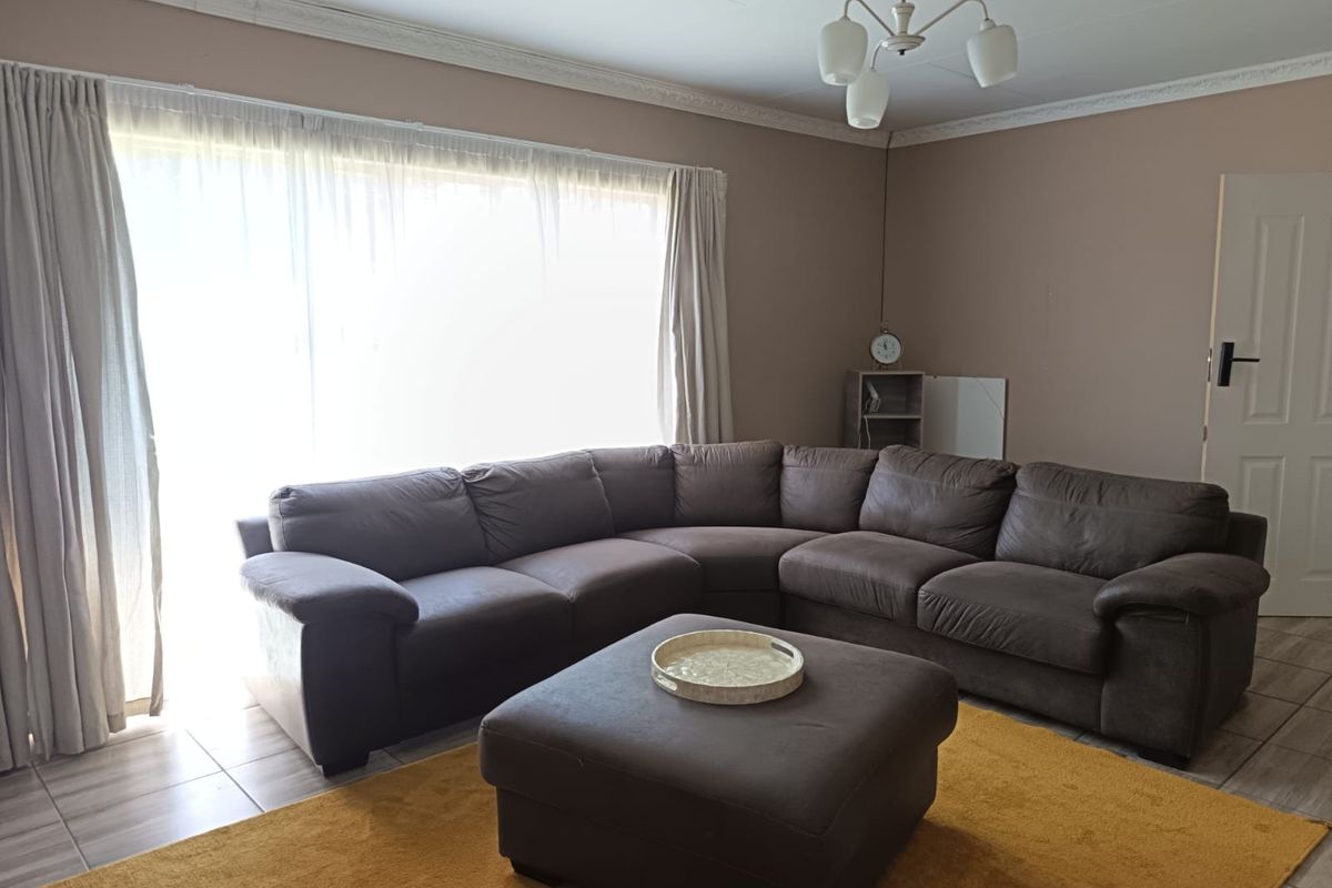 A living room featuring tiled flooring, decorative ceiling cornices, and a central light fixture, providing a neutral base for interior updates.