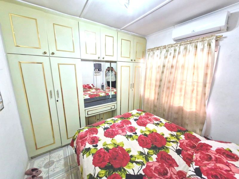 A bedroom featuring built-in cabinetry with an integrated vanity mirror, tiled flooring, and a wall-mounted split-system air conditioning unit.