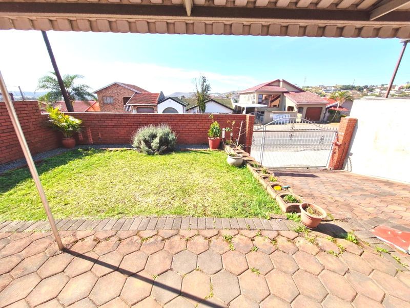 A covered patio area overlooking a small private garden with brick boundary walls and paved flooring.