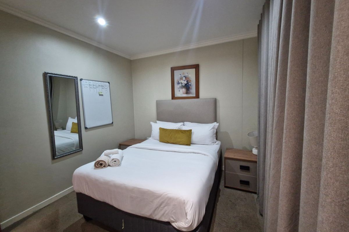 A well-maintained bedroom featuring neutral wall tones, recessed downlighting, and carpeted flooring, providing a comfortable and functional living space.