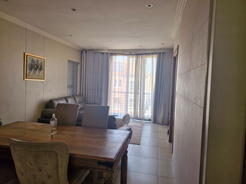 Open plan living and dining area featuring tiled floors, recessed lighting, and large sliding glass doors leading to a balcony.