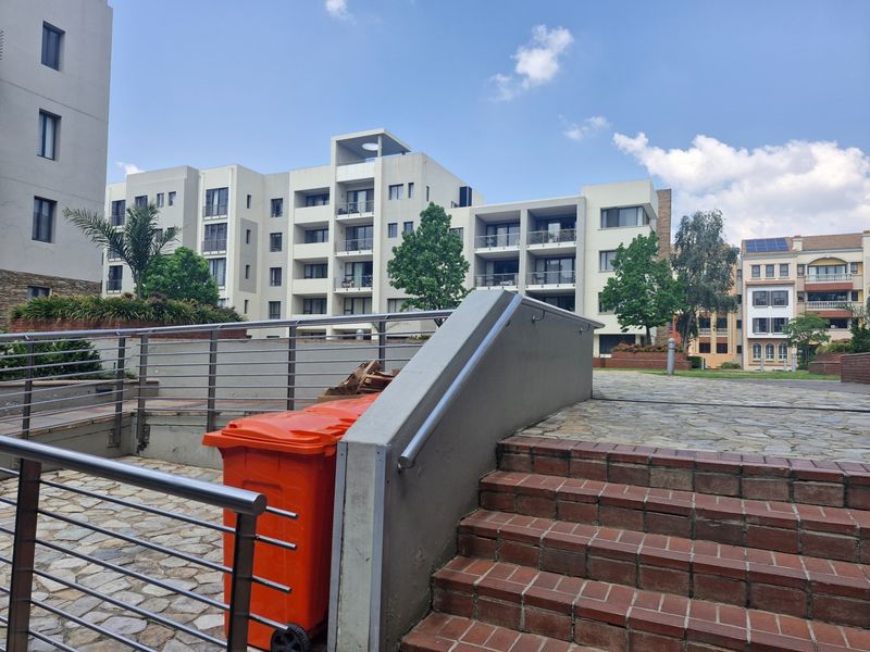 Exterior view of an apartment complex featuring stone paved walkways, brick stairs with stainless steel handrails, and landscaped garden areas.