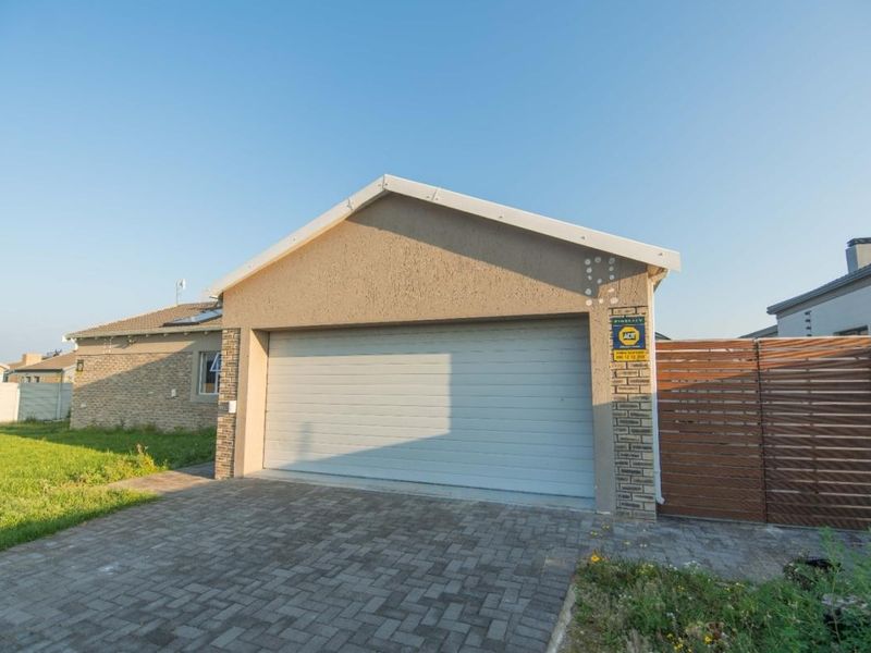 Front view of the property featuring a paved driveway, a single sectional garage door, and a timber side gate.
