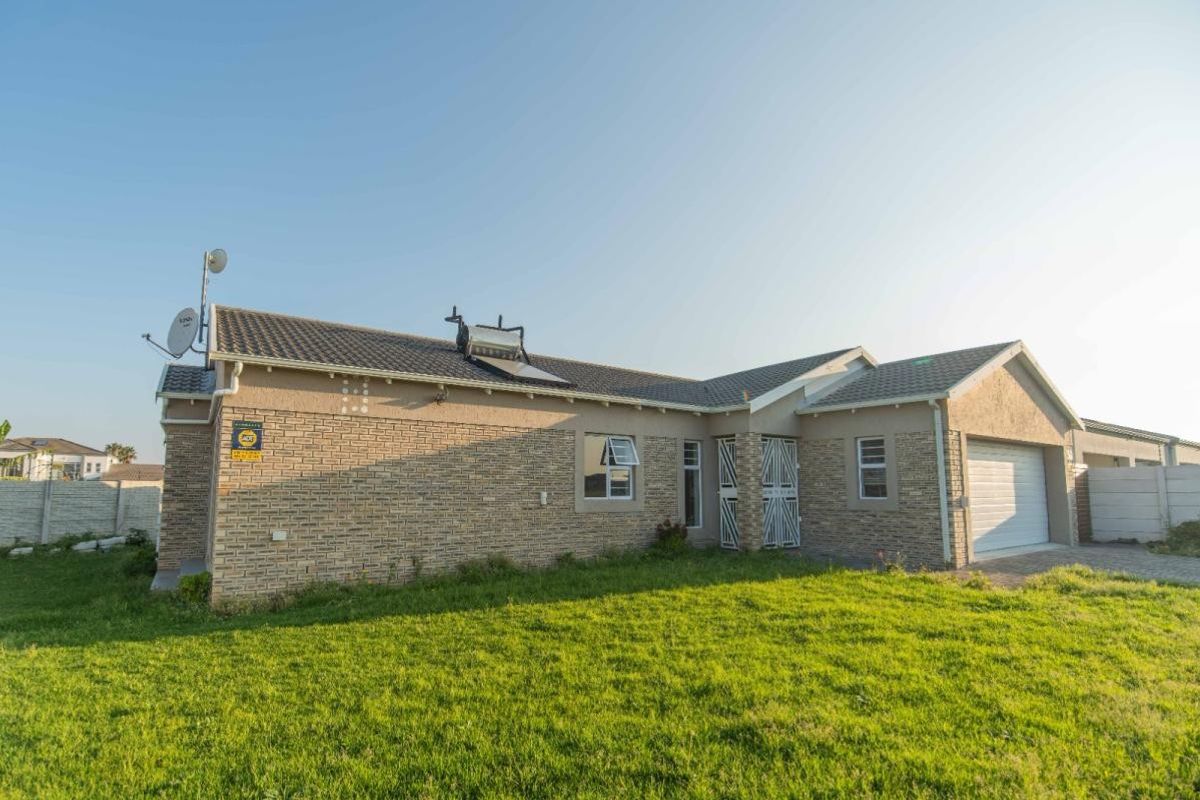 Rear view of a single-story brick house featuring a solar water heater, security gate, and an attached garage with a paved driveway.
