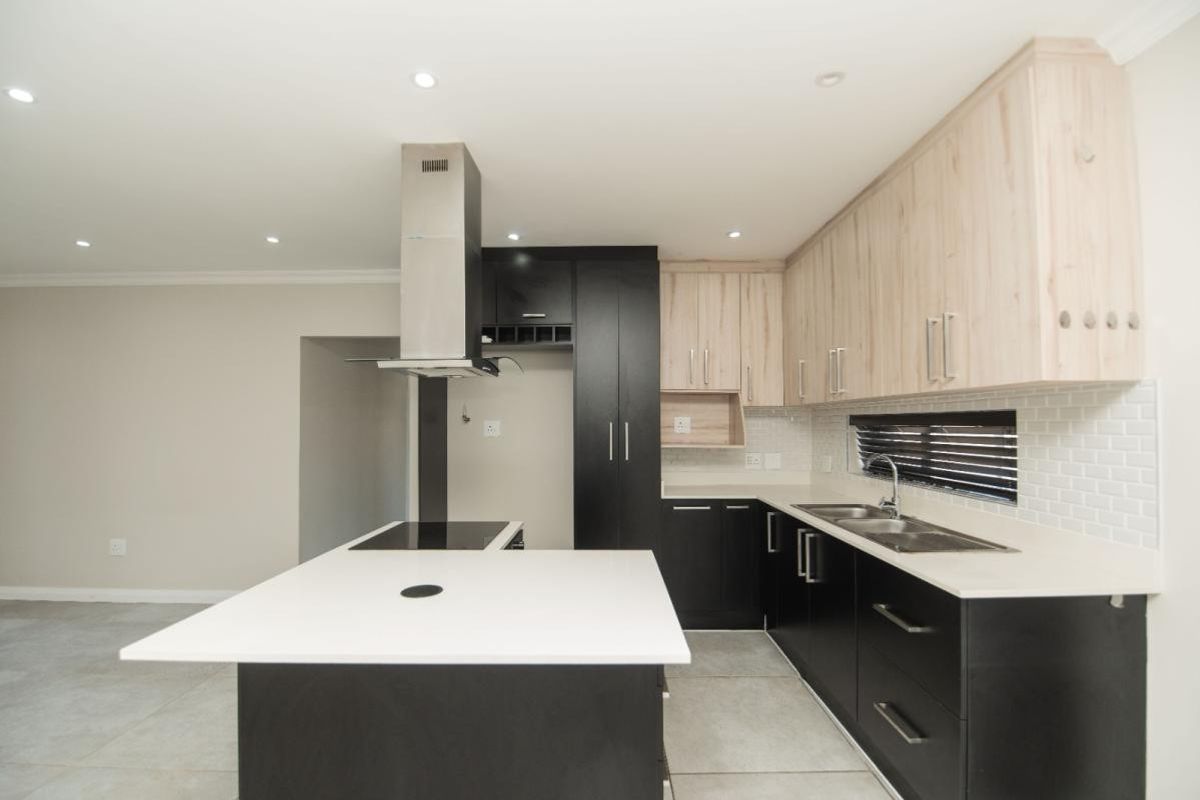 Modern kitchen featuring a central island, two-tone cabinetry, quartz countertops, subway tile backsplash, and integrated stainless steel appliances.